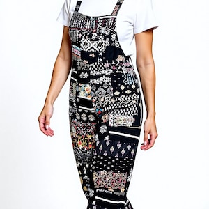 Puede incluir: Una mujer con un mono negro con diseño de patchwork. Lleva una camiseta blanca debajo y zapatillas blancas. El patchwork presenta varios patrones en colores como rojo, blanco y amarillo.