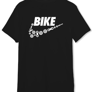 Könnte beinhalten: Schwarzes T-Shirt mit einem weißen Aufdruck des Wortes "BIKE" mit einem Swoosh aus Fahrradkettengliedern.