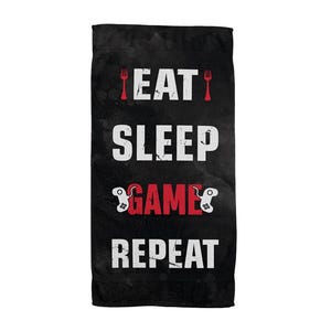 Könnte beinhalten: Schwarzes rechteckiges Handtuch mit den Worten "EAT SLEEP GAME REPEAT" in Weiß und Rot. Das Wort "GAME" ist rot mit einer Videospiel-Controller-Grafik. Die Wörter sind vertikal gestapelt.