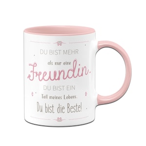 Könnte beinhalten: Weiße Keramiktasse mit rosafarbenem Rand und Henkel. Die Tasse hat eine rosafarbene Aufschrift mit dem Text "DU BIST MEHR als nur eine Freundin. DU BIST EIN Teil meines Lebens. Du bist die Beste!"