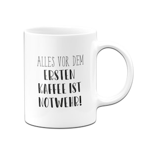 Könnte beinhalten: Weiße Keramik-Kaffeetasse mit schwarzem Text, der "Alles vor dem ersten Kaffee ist Notwehr!" lautet.