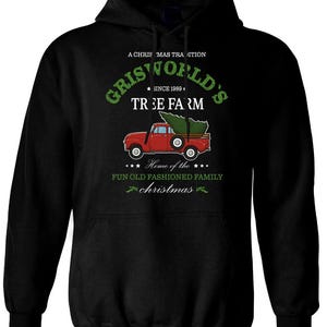Könnte beinhalten: Schwarzer Kapuzenpullover mit einem Grafikdesign eines roten Lastwagens mit einem Weihnachtsbaum. Der Text lautet "Griswold's Tree Farm" und "A Christmas Tradition" in Grün, mit "Since 1989" und "Home of the Fun Old Fashioned Family Christmas".