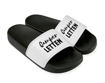 Könnte beinhalten: Ein Paar schwarze und weiße Schlappen mit dem Text "Campen Letten" auf den weißen Riemen.