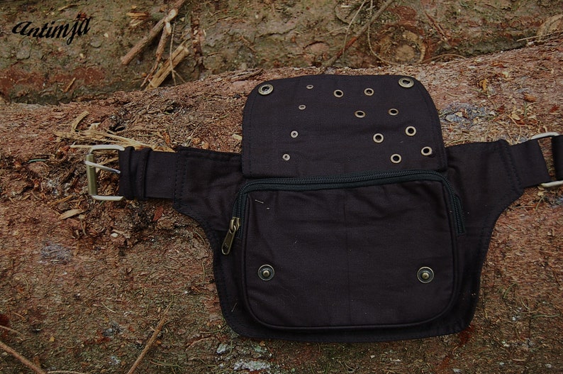 May include: A black canvas fanny pack with a zippered pocket and multiple grommets. The pack has a buckle closure and a strap.