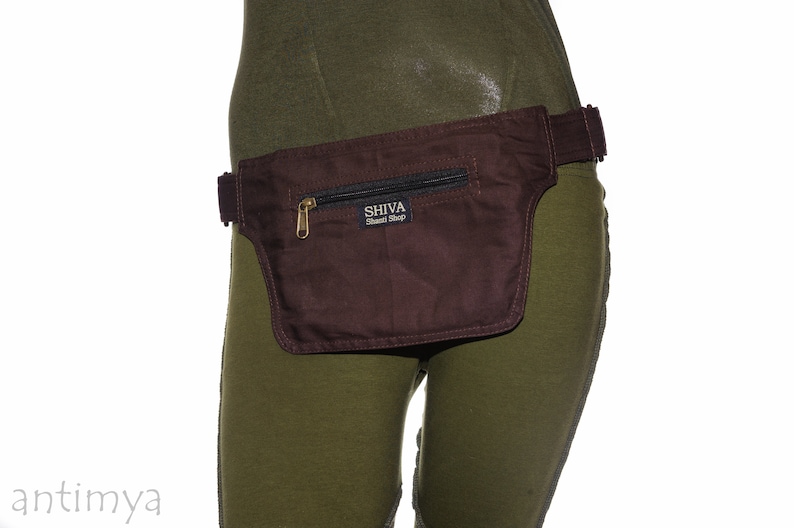 May include: A brown canvas fanny pack with a zippered pocket and a black strap. The fanny pack has a gold zipper and a label that reads "SHIVA Tribal Shop".