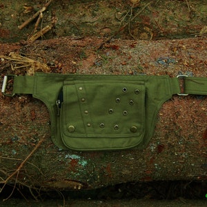 May include: A green canvas fanny pack with metal rivets and eyelets. The pack has a zippered pocket and a belt loop.