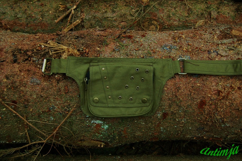 May include: A green canvas fanny pack with metal rivets and eyelets. The pack has a zippered pocket and a belt loop.
