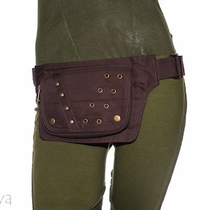 May include: A brown canvas fanny pack with a flap closure and metal accents. The fanny pack is worn around the waist and has a strap that can be adjusted.