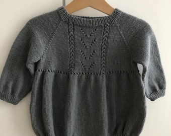 May include: A gray knitted baby onesie with long sleeves and a button closure. The onesie has a delicate cable knit pattern on the front.