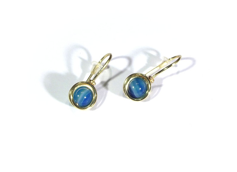 May include: A pair of gold earrings with blue and white agate stones. The earrings are made with a simple wire design.