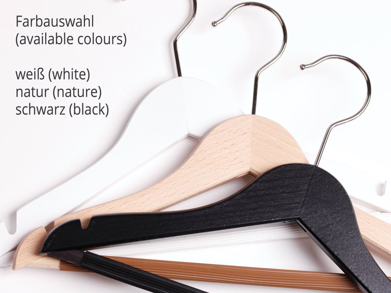 May include: Three wooden hangers in white, natural wood, and black. The text "Farbauswahl (available colours)" is written above the hangers. Below the text are the words "wei&szlig; (white)", "natur (nature)", and "schwarz (black)".