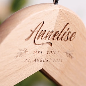 May include: A wooden hanger with the name "Annelise" engraved on it, along with the text "MRS. VOIGT" and "23. AUGUST 2021".