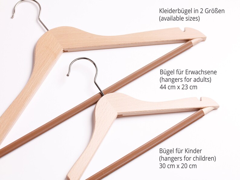 May include: Two wooden hangers, one larger and one smaller, with brown fabric covered bars. The larger hanger measures 44 inches by 23 inches and the smaller hanger measures 30 inches by 20 inches. The text "Kleiderb&uuml;gel in 2 Gr&ouml;&szlig;en (available sizes)" is at the top of the image. The text "B&uuml;gel f&uuml;r Erwachsene (hangers for adults) 44 cm x 23 cm" is in the middle of the image. The text "B&uuml;gel f&uuml;r Kinder (hangers for children) 30 cm x 20 cm" is at the bottom of the image.