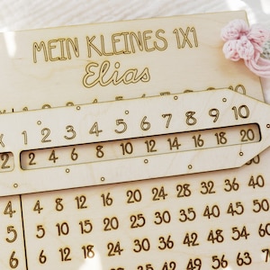 Può includere: Tabella di moltiplicazione in legno con un righello scorrevole per imparare la matematica. La tabella è etichettata "Mein Kleines 1x1 Elias".