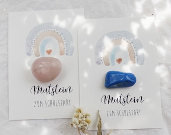 Könnte beinhalten: Zwei Karten mit Aquarell-Regenbogen-Designs und Edelsteinen. Eine Karte zeigt einen rosa Edelstein, die andere einen blauen Edelstein. Der Text "Mutstein ZUM SCHULSTART" ist in einer Schreibschrift unter dem Regenbogen und Edelstein geschrieben.
