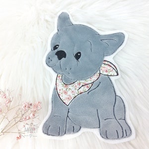 Könnte beinhalten: Ein grauer Plüsch-Französisch-Bulldogge mit einem Bandana mit Blumenmuster. Der Hund sitzt aufrecht mit den Pfoten nach vorne. Das Plüschtier hat schwarze Augen und Nase und einen weißen Umriss.