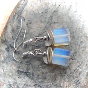 Könnte beinhalten: Ein Paar silberne Ohrhänger mit einem blauen und weißen Opal-Würfel-Anhänger an jedem Ohrring.