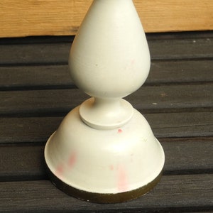 May include: White ceramic candlestick with a gold rim. The candlestick has a bulbous base and a tall, slender stem.
