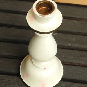May include: White ceramic candle holder with a gold rim and a brass candle cup.