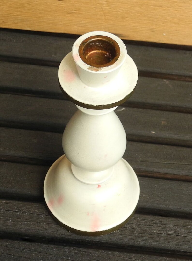 May include: White ceramic candle holder with a gold rim and a brass candle cup.