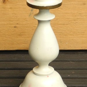 May include: White ceramic candle holder with a gold trim. The holder has a round base and a tall, slender body with a flared top.