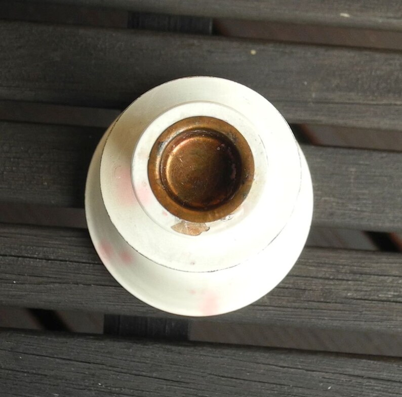 May include: White ceramic candle holder with a gold metal insert. The holder has a slightly scalloped edge.