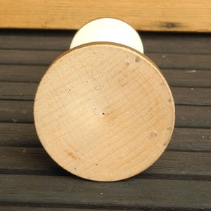 May include: The bottom of a white ceramic vase with a wooden base. The base is marked with the number "528".