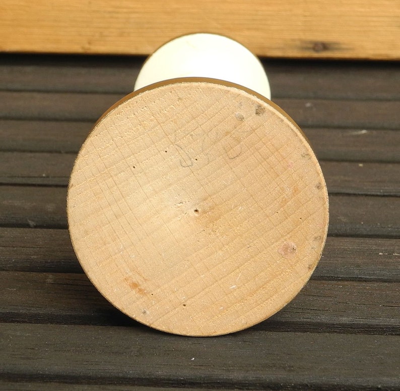 May include: The bottom of a white ceramic vase with a wooden base. The base is marked with the number "528".