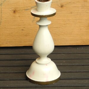 May include: White ceramic candle holder with a gold rim and a simple, elegant design. The holder has a round base and a tall, slender body.