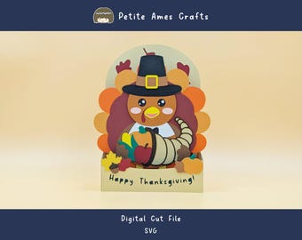 May include: A Thanksgiving-themed papercraft featuring a cartoon turkey wearing a pilgrim hat, holding a cornucopia filled with fruits and vegetables. The design includes the text "Happy Thanksgiving!" and is labeled as a digital cut file.