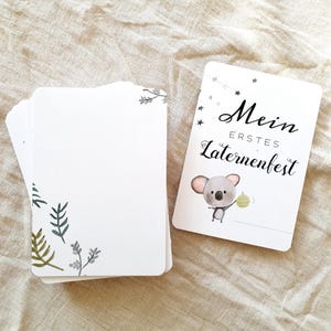 May include: A white card with a koala holding a lantern. The card says "Mein erstes Laternenfest" which translates to "My first lantern festival".