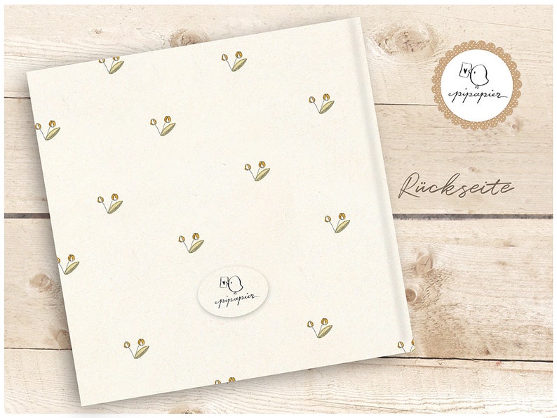 May include: A white card with a repeating pattern of small green leaves and yellow dots. The card has a white oval sticker with a small bird illustration and the text "pippapier" in black. The text "R&uuml;ckseite" is printed in black on a wooden surface.