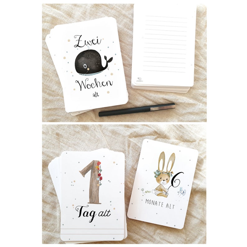 May include: A set of baby milestone cards with illustrations of a whale, a bunny, and a tree. The cards are white with black and brown illustrations and text. The text on the cards reads "Zwei Wochen alt", "1 Tag alt", and "6 Monate alt".