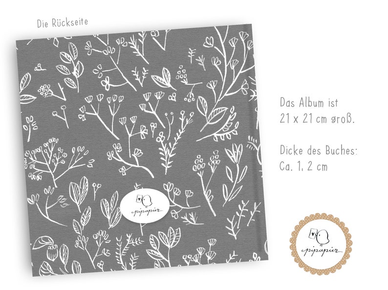 May include: A gray fabric cover with a white floral pattern. The text "Die R&uuml;ckseite" is at the top of the cover. The text "Das Album ist 21 x 21 cm gro&szlig;. Dicke des Buches: Ca. 1, 2 cm" is on the right side of the cover. A white circle with the text "pipapier" is in the center of the cover.