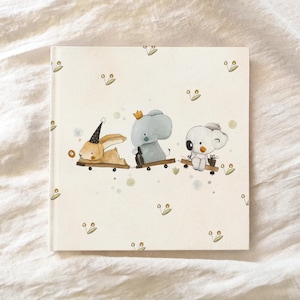 May include: A white card with a light brown bunny, a gray elephant, and a white koala riding on toy trains. The background is white with a light green floral pattern.