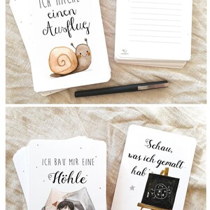 May include: A set of cards with illustrations and text in German. The cards feature a snail, a child building a fort, and a child drawing a ladybug on a chalkboard. The text on the cards reads "Ich mache einen Ausflug", "Ich bau mir eine H&ouml;hle", and "Schau, was ich gemalt hab".