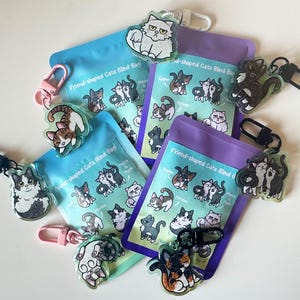 Peut inclure: Un ensemble de six sachets aveugles colorés, chacun contenant un porte-clés en forme de chat différent. Les sachets sont étiquetés "Friend-shaped Cats Blind Bag".