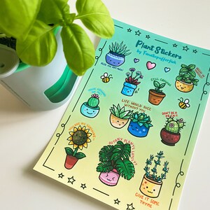 May include: A sheet of colorful plant stickers with cute illustrations and puns. The stickers feature various plants, including succulents, cacti, and a sunflower. The text on the stickers includes phrases like "Aloe You Very Much", "Still Growing", and "Life Would Suck Without You".