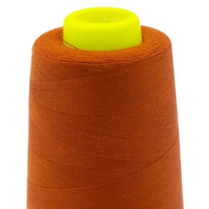 Könnte beinhalten: Eine Spule orangefarbenen Garns mit einem gelben Plastikdeckel.