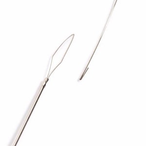 May include: Two silver metal tools for threading beads. One tool has a pointed end and the other has a loop at the end.