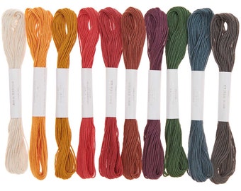 May include: Ten spools of embroidery floss in various shades of red, orange, yellow, green, blue, and brown. The floss is wound around white cardboard spools with the brand name "RICO DESIGN" printed on them.