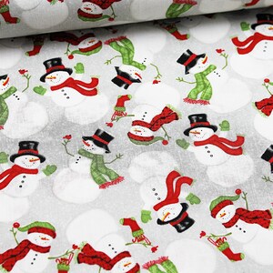 Peut inclure: Un tissu blanc avec un motif répété de bonhommes de neige portant des écharpes et des chapeaux rouges et verts. Les bonhommes de neige sont sur un fond gris.