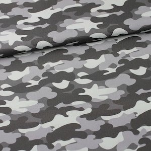 Peut inclure: Tissu camouflage gris et blanc avec un motif marbré. Le tissu est plié en deux, montrant le motif des deux côtés.