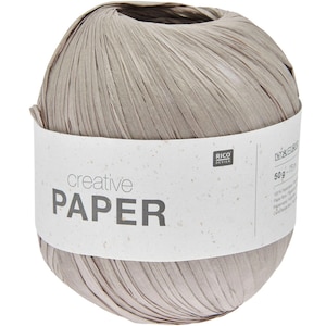 Pode incluir: Uma bola de fio de papel cinza com um rótulo branco que diz "creative PAPER" e "RICO DESIGN". O rótulo também inclui o texto "50g - 75m" e "100% Papel reciclado".