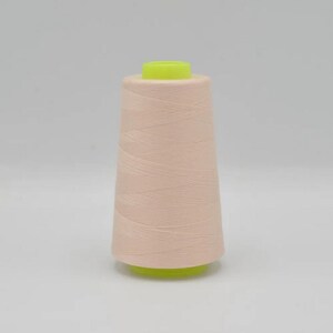 May include: A spool of pale pink thread with a yellow plastic top and bottom.
