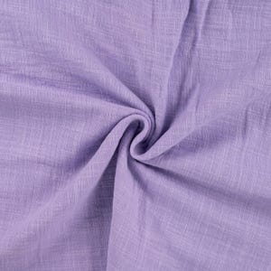 Könnte beinhalten: Nahaufnahme eines weichen, strukturierten Stoffes in Lavendelfarbe. Der Stoff hat ein dezentes gewebtes Muster und eine leicht zerknitterte Optik.