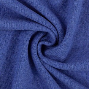 Puede incluir: Primer plano de una tela de punto azul con una superficie suave y texturizada. La tela est&aacute; doblada y drapeada, creando una curva suave y fluida.