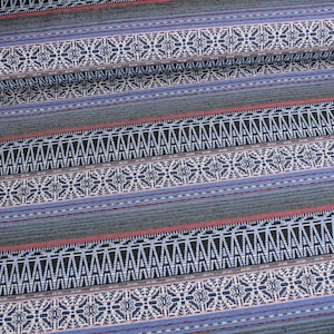 Pode incluir: Tecido listrado azul e preto com um padrão geométrico. O padrão apresenta acentos brancos e rosados.