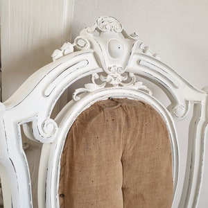 Puede incluir: Silla blanca pintada con un acabado desgastado y un asiento de tela marr&oacute;n. La silla tiene un dise&ntilde;o tallado y adornado.