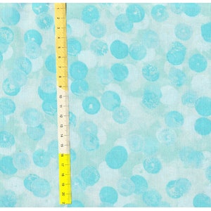Peut inclure: Un tissu bleu clair avec un fond blanc et un motif répétitif de cercles bleus clairs. Une règle jaune est sur le côté droit de l'image.